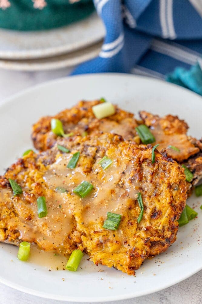 breaded chicken fried steak on a white plate in front of an air fryer 