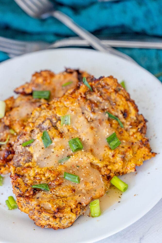 breaded chicken fried steak on a white plate in front of an air fryer 