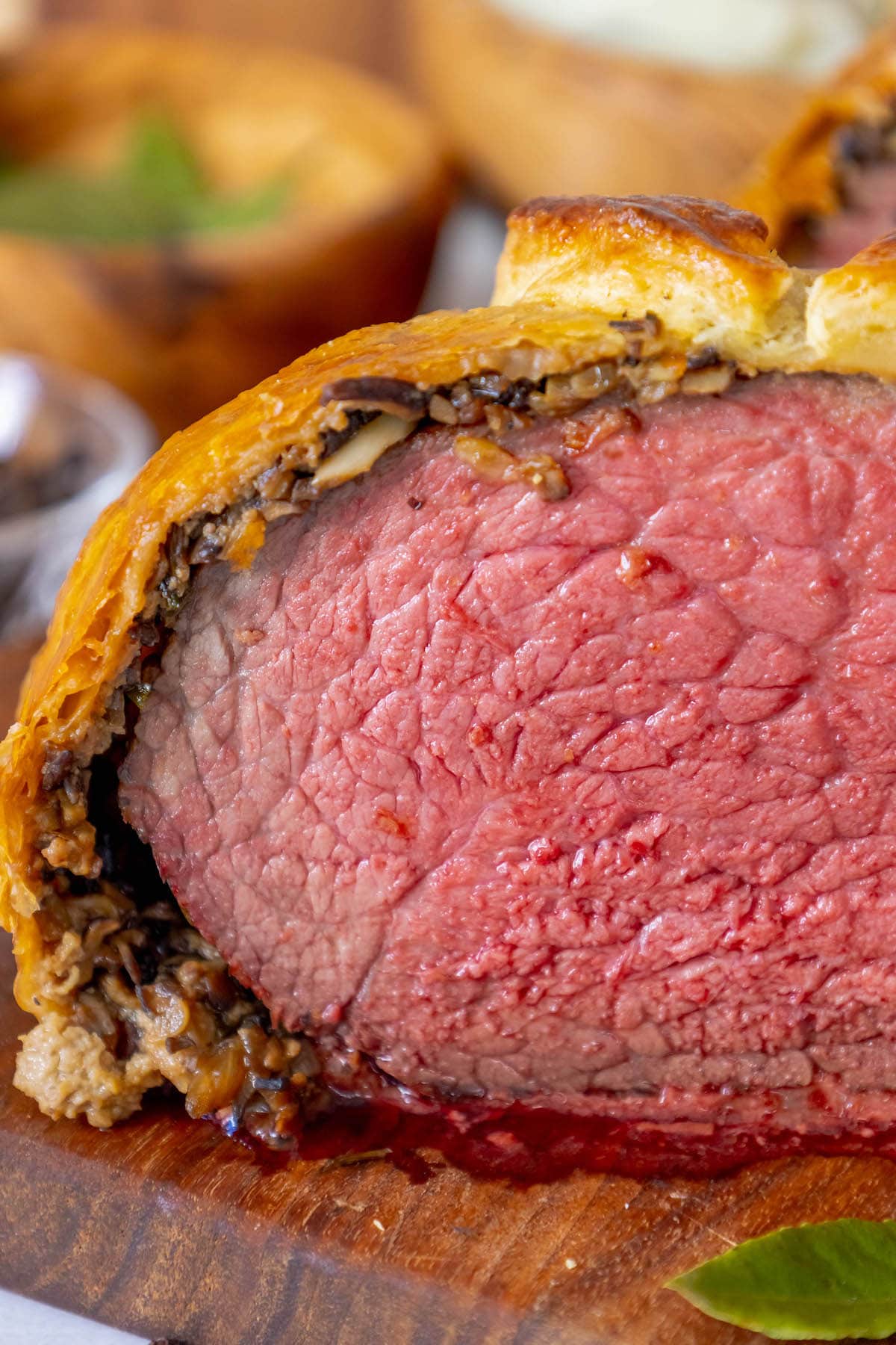 beef wellington wrapped in puff pastry sliced in half sitting on a cutting board